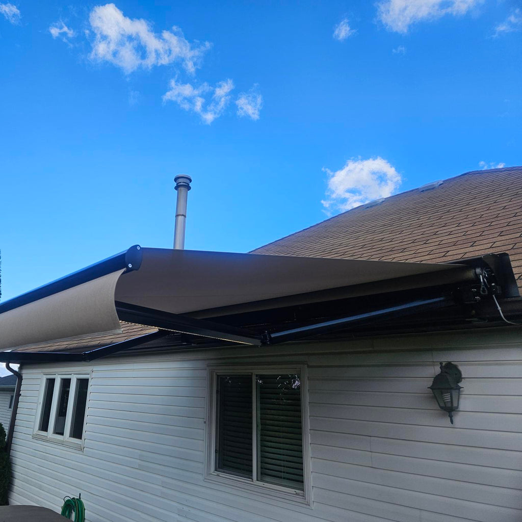 House with a partially extended awning on a clear blue sky day.